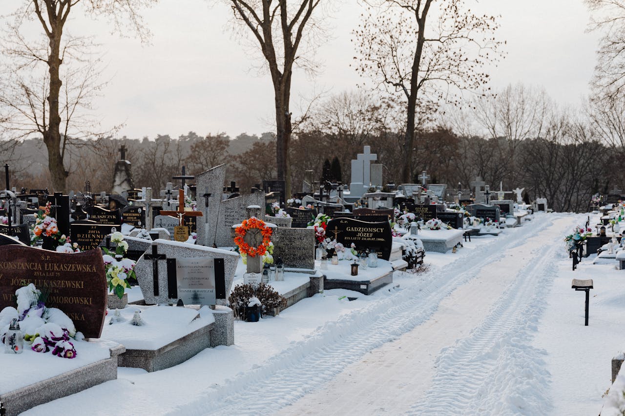 services-img A peaceful snow-covered cemetery with gravestones under a winter sky, invoking serenity.